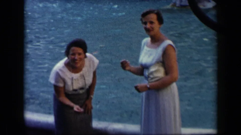 1960 Vatican, Italy home-movie frame showing two adult women smiling near water, with visible grain and handheld framing.