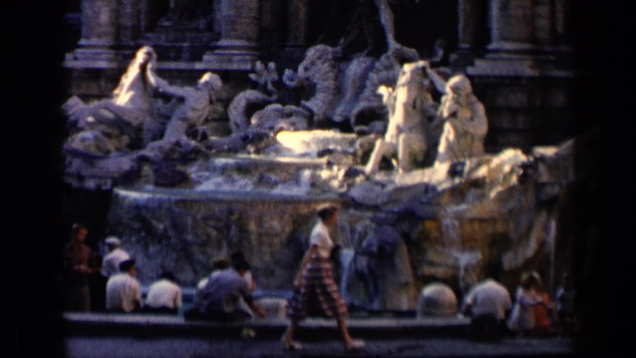 Trevi Fountain sculptures with tourists seated and walking near the basin.