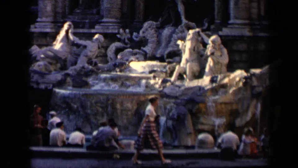 1960 8mm view of the Trevi Fountain in Rome with sculptural figures above tourists gathered at the base.