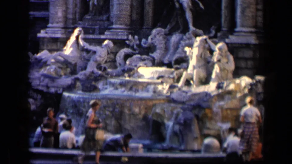 Home-movie frame of the Trevi Fountain in Rome, with tourists clustered at the lower edge of the water.