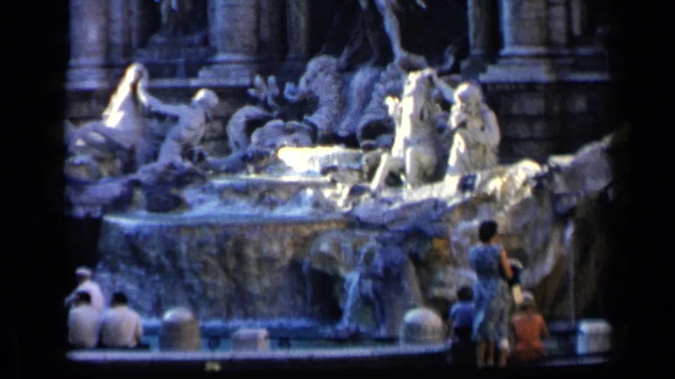 1960 8mm closer view of Rome's Trevi Fountain, showing sculpture, cascading water, and tourists near the lower rim.