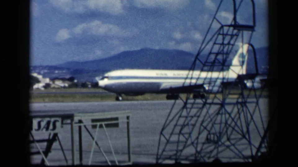 The Pan Am Boeing 707 continues taxiing behind mobile stairs at an Italian airport, with runway pavement, hills, and sky in the background.
