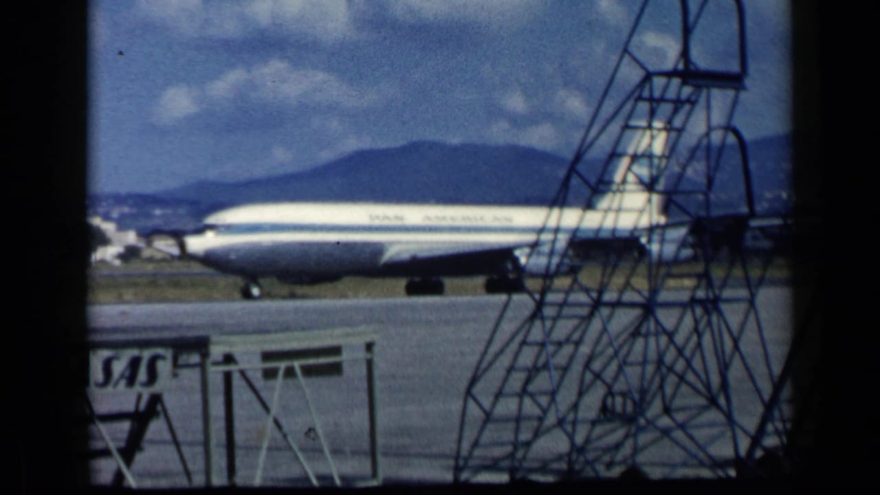 Pan American jet taxiing on a runway with mobile stairs and SAS sign in the foreground.