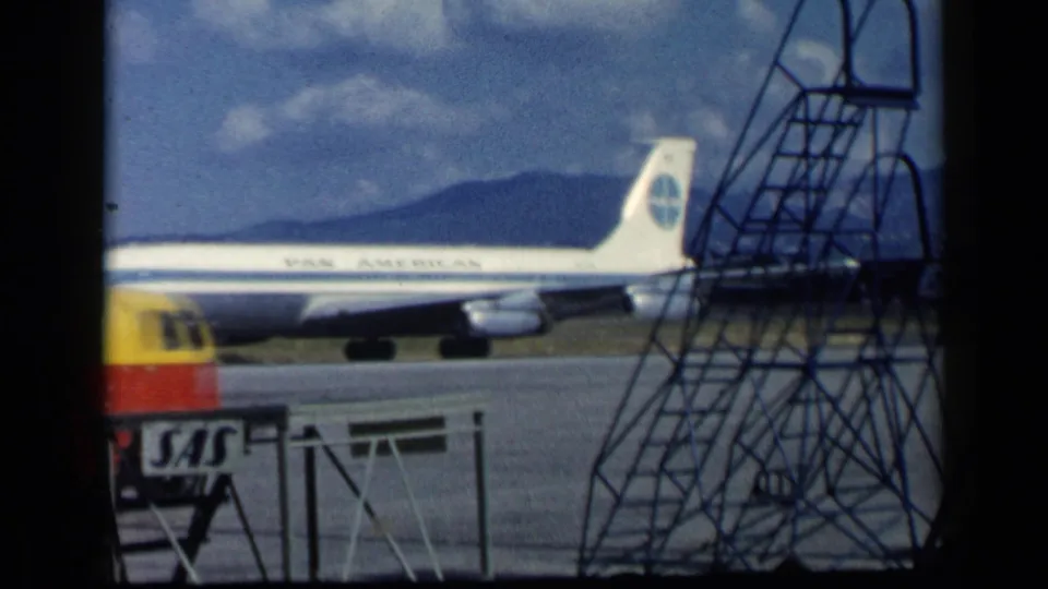 Pan American Boeing 707 continues taxiing while a Shell fuel truck crosses the foreground near metal stairs and SAS signage.