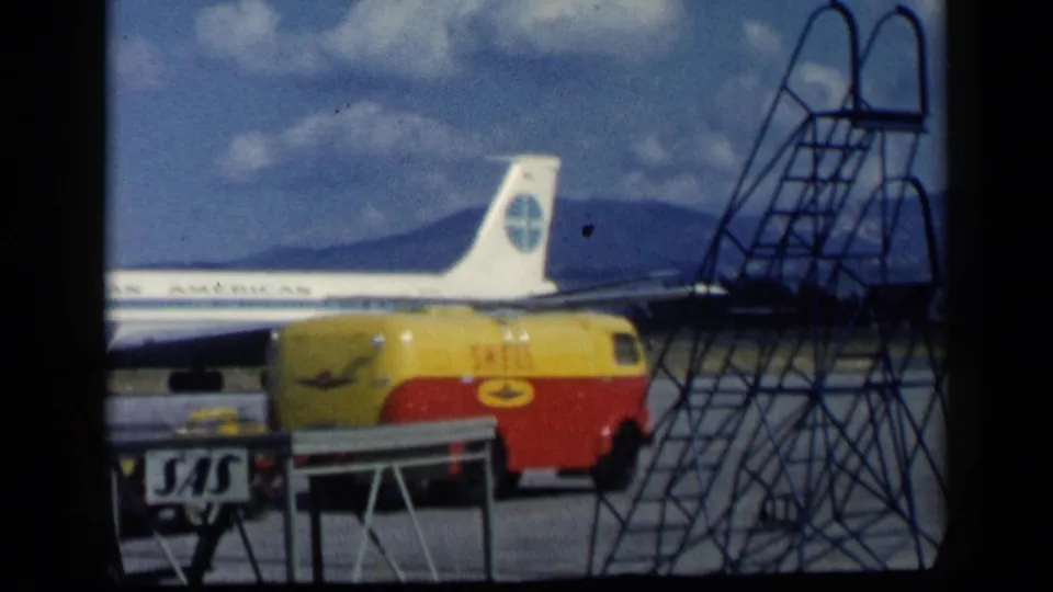 A Shell fuel truck and metal stair structure obscure part of the Pan American aircraft in this 1960 airport runway view.