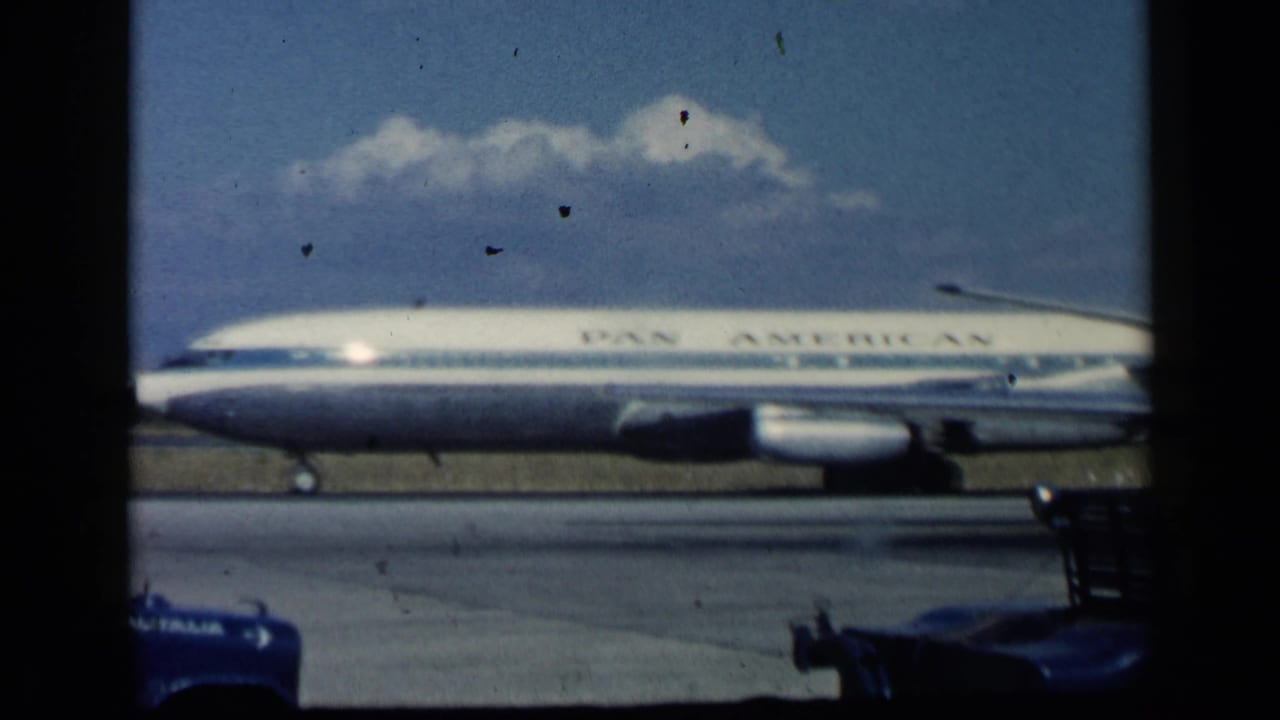 Pan American jet moving along a runway under a blue sky.