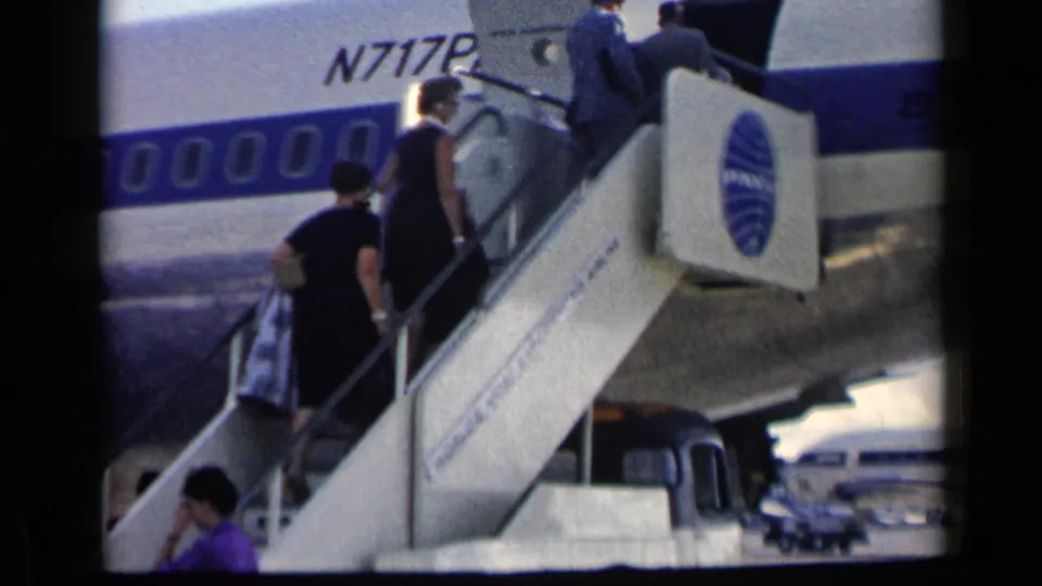 1960 Vatican, Italy footage shows travelers boarding a Pan Am Boeing airliner by mobile stairs, with N717P visible on the fuselage.