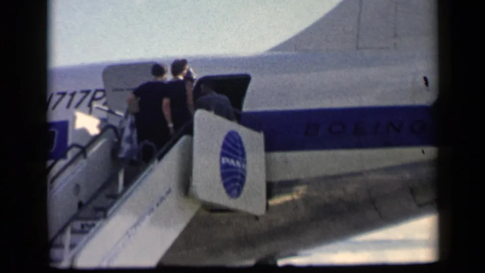 Passengers in period clothing wait near the open door of a Pan Am Boeing aircraft during boarding in the 1960 Vatican, Italy clip.