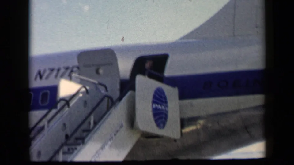 Near the end of the clip, the open door, Pan Am-marked stairs, and Boeing fuselage remain in view with few people visible.