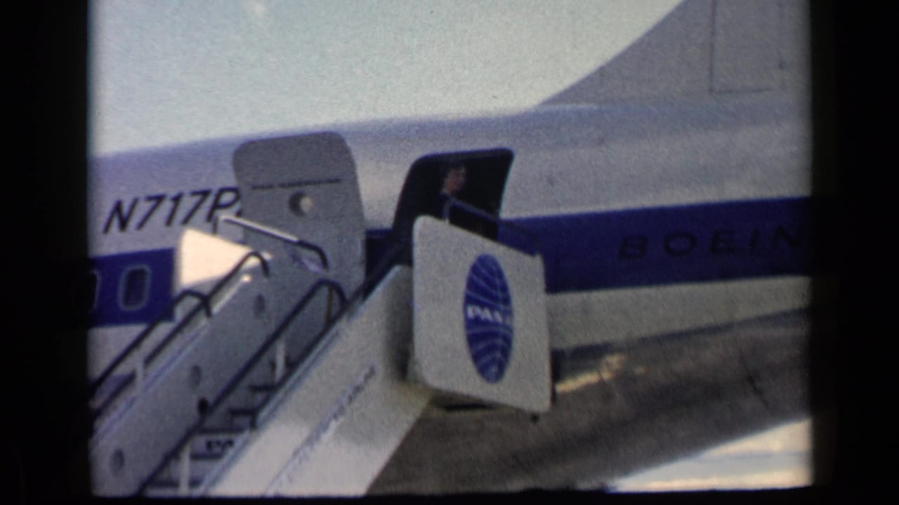 Pan Am aircraft fuselage with open door and boarding stairs on the tarmac.