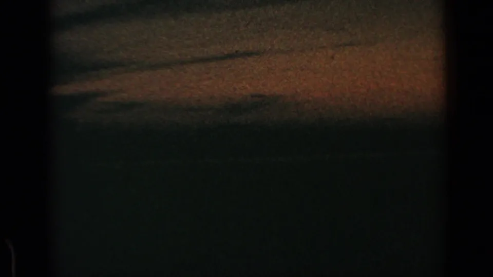 End of the 1960 8mm road view, with dusk-like exposure over blurred fields and roadside ground from a moving vehicle.