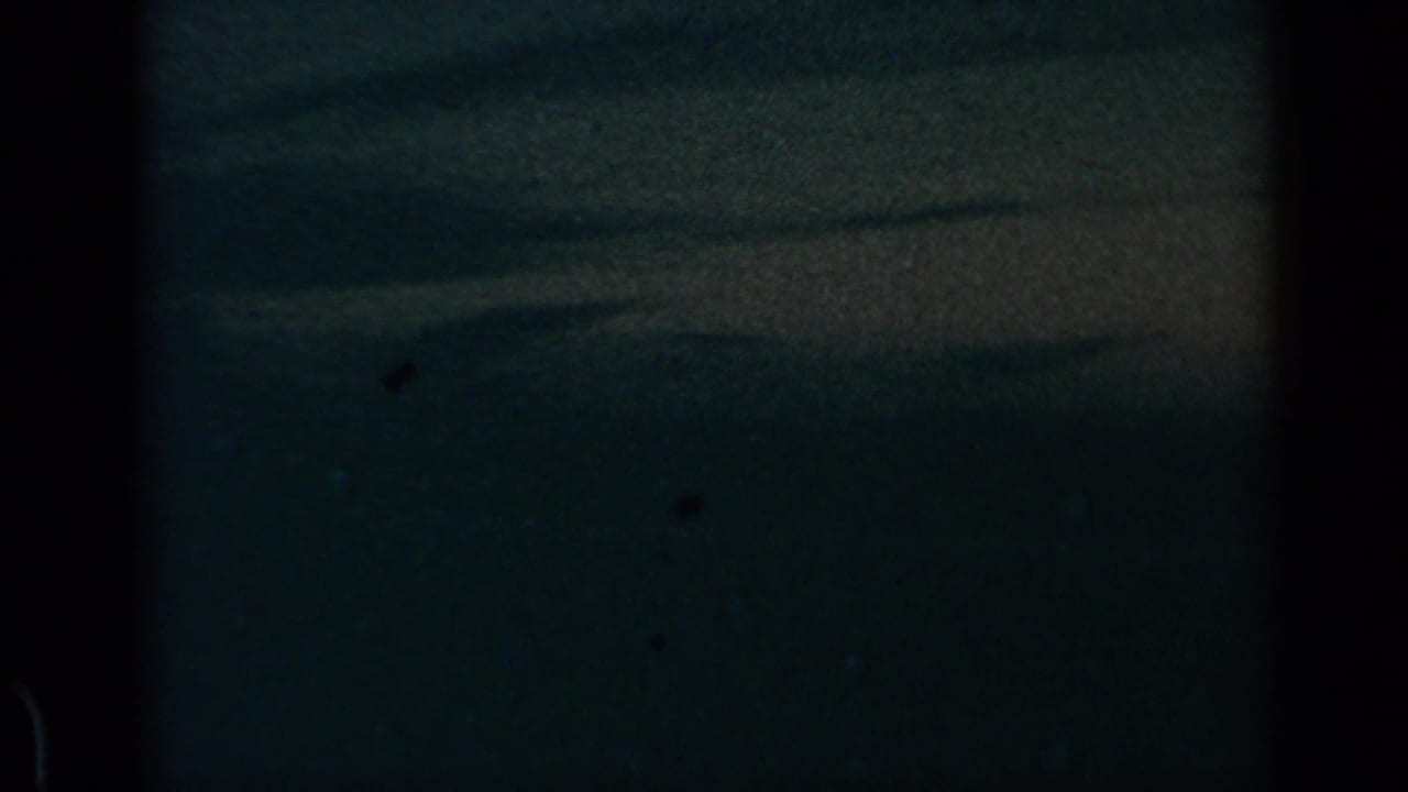 1960 8mm travel footage showing a subdued cloud horizon through dark airplane-window framing.