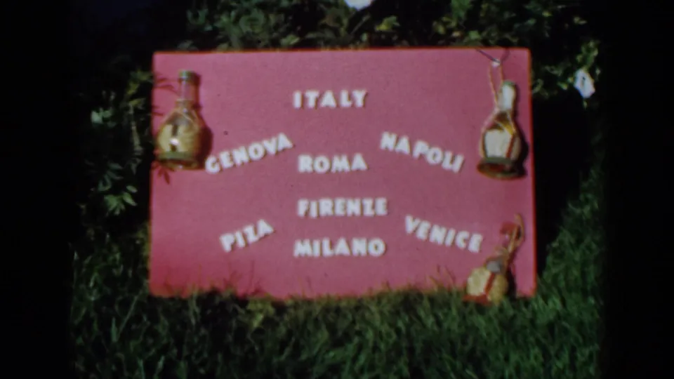 Clearer 1960 Venice frame of a pink decorative sign with Italian city names and glass carafe ornaments.