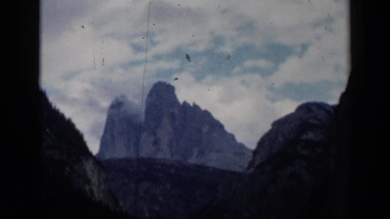 Misty mountain peaks seen through a dark film-frame opening.