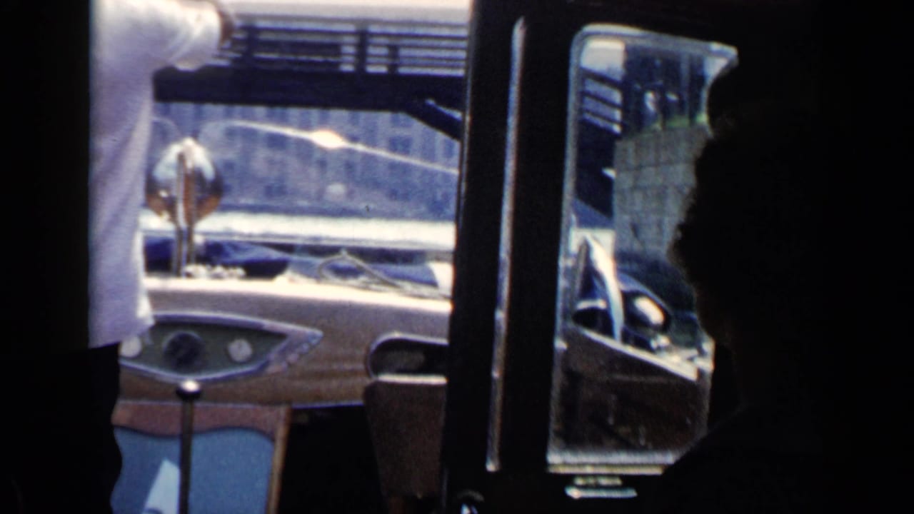 1960 Venice boat-ride view from inside a small motorboat, with passengers in shadow and canal structures beyond the windshield.