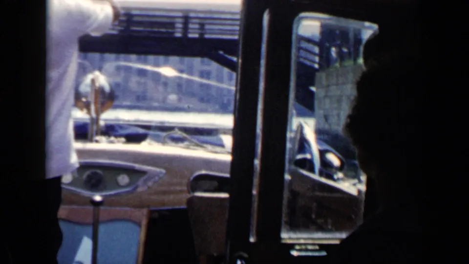 1960 Venice boat-ride view from inside a small motorboat, with passengers in shadow and canal structures beyond the windshield.