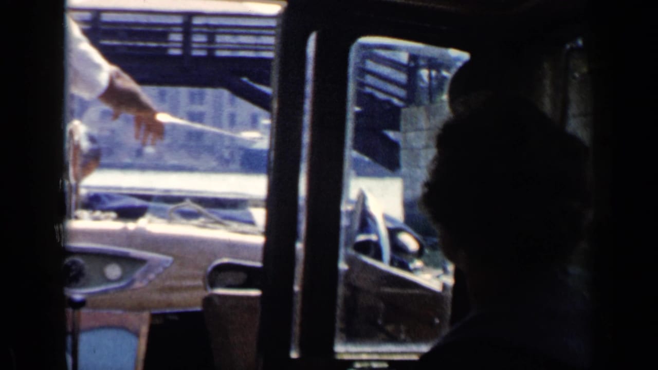 Passenger-level 1960 Venice canal footage showing a motorboat dashboard, windshield, and seated figure in shadow.