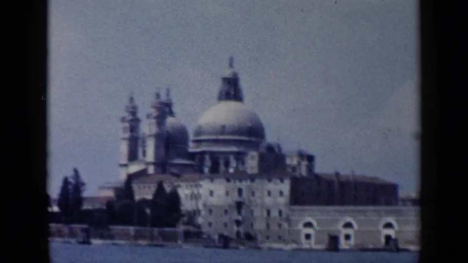 A domed historic waterfront building in Venice appears across the water in soft 8mm focus.