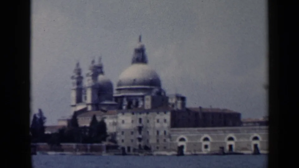 Venice waterfront view of Santa Maria della Salute on 8mm film, with the basilica framed by water and dark reel borders.