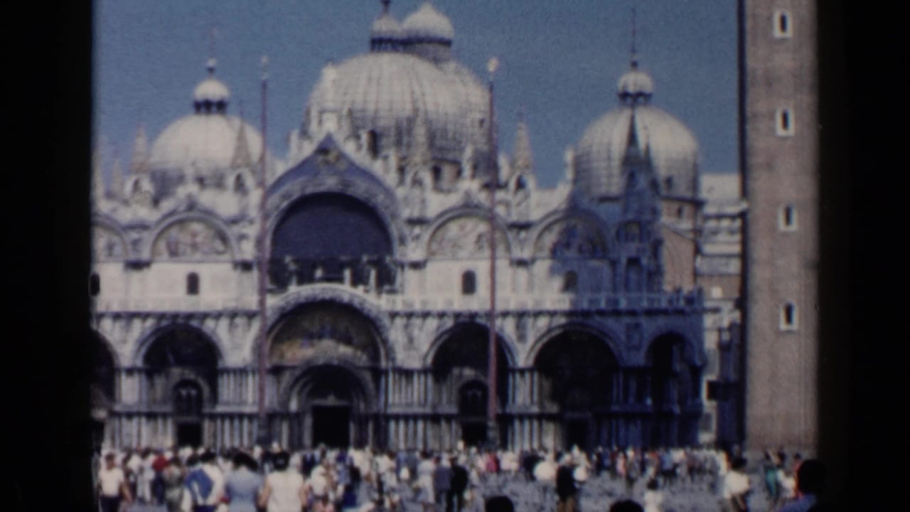 Wide view of St. Mark's Basilica with domes, arches, campanile edge, and tourists in the square.