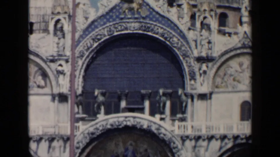 Closer 1960 8mm detail of St. Mark's Basilica in Venice, centered on a large decorated arch, mosaics, sculptures, and balcony stonework.