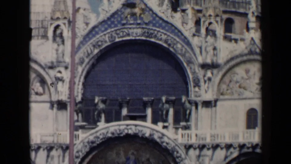 Close 1960 Venice frame of St. Mark's Basilica facade, showing ornate arch decoration, mosaic areas, carved figures, and a balcony below.