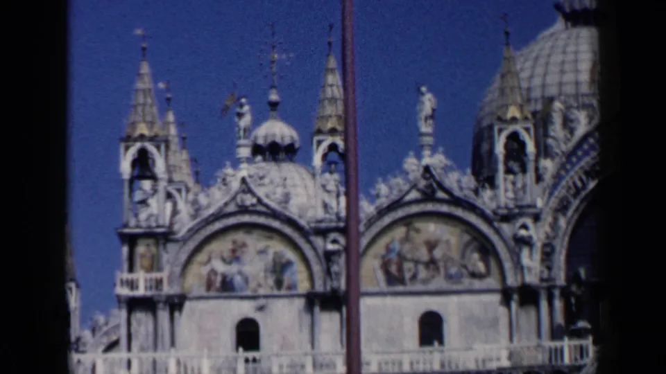 1960 Venice frame of St. Mark's Basilica showing mosaic arch panels, spires, rooftop statues, ornate stonework, and part of a dome.