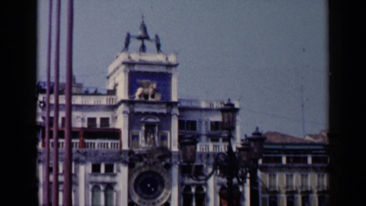 1960 Venice footage shows more of the St. Mark's Square clock tower facade, including the clock face and surrounding architecture.