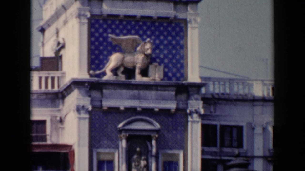 Winged lion statue on a blue patterned building facade with pale stone columns.
