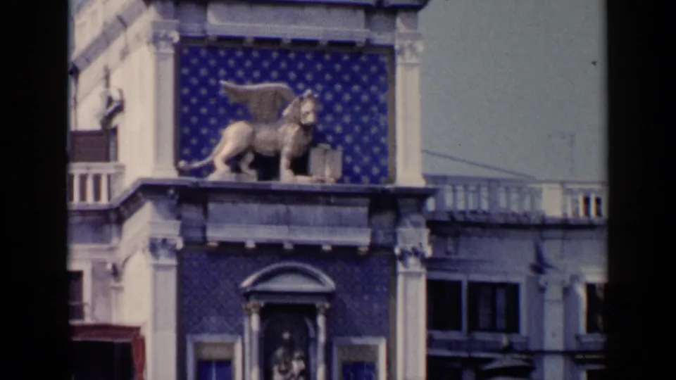 1960 Venice 8mm frame with the winged lion-like sculpture more centered on the blue tiled facade.