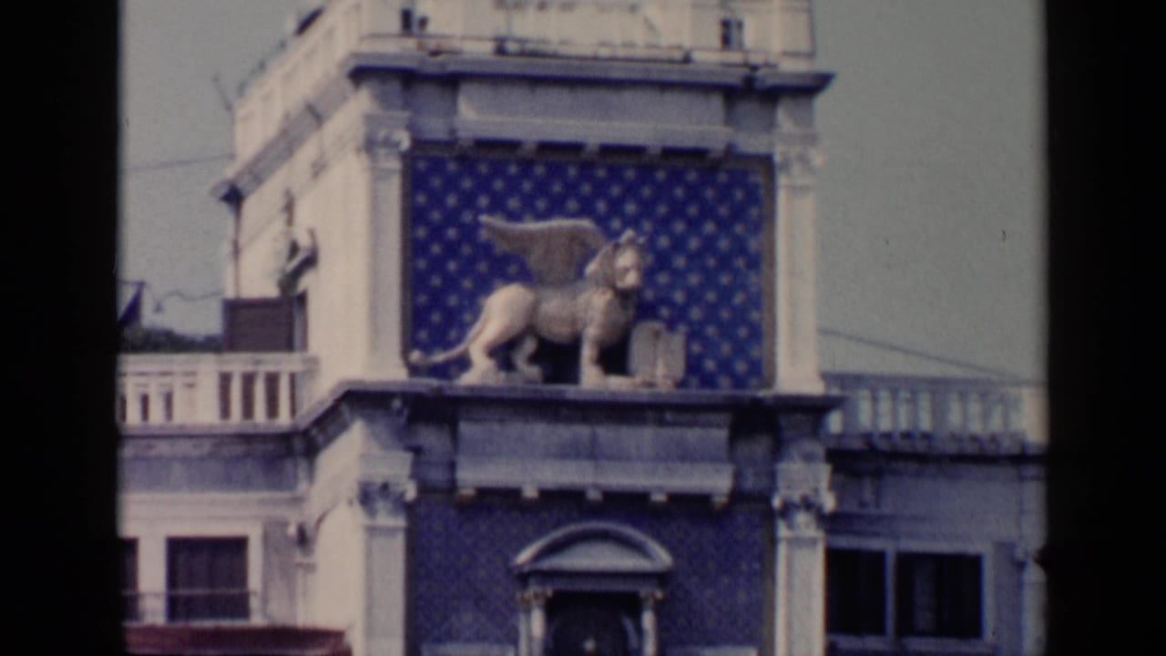Winged lion sculpture on a building facade with blue patterned wall panels.