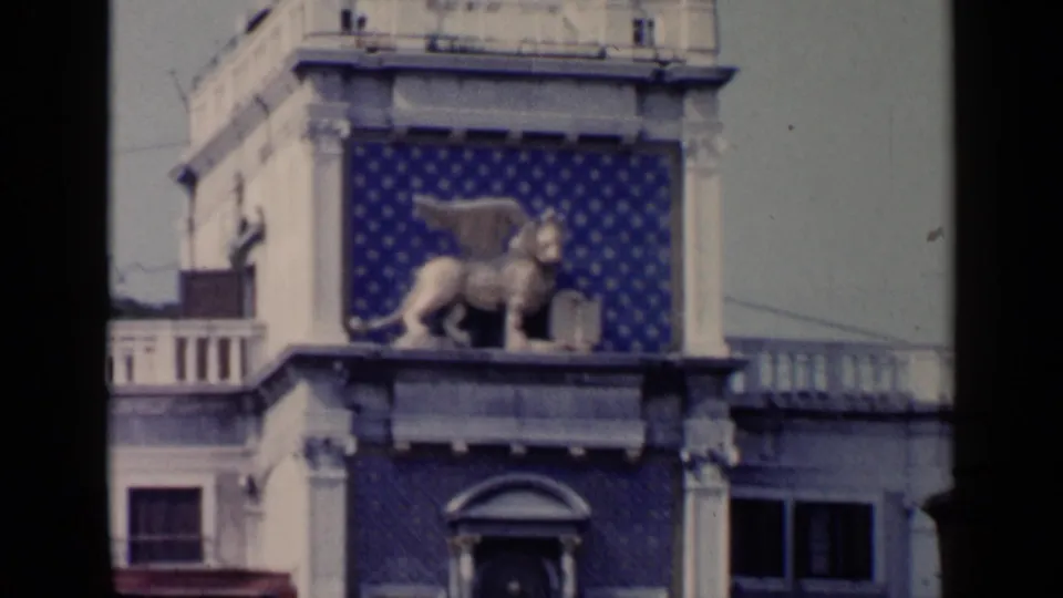 1960 Venice 8mm frame with the winged lion of St. Mark on a decorated facade, framed by soft focus and film edge shadow.