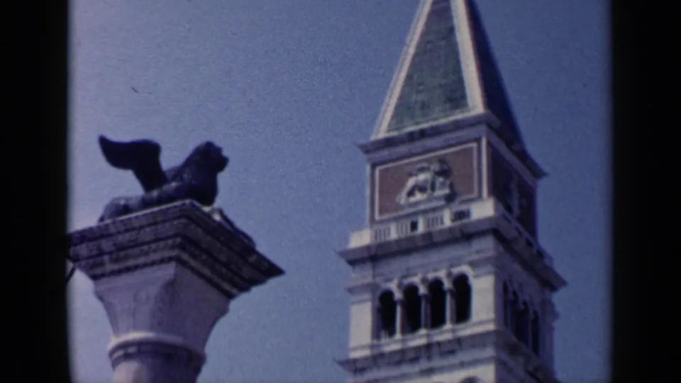 1960 Venice 8mm frame showing the Campanile di San Marco beside the winged lion column in Piazza San Marco.