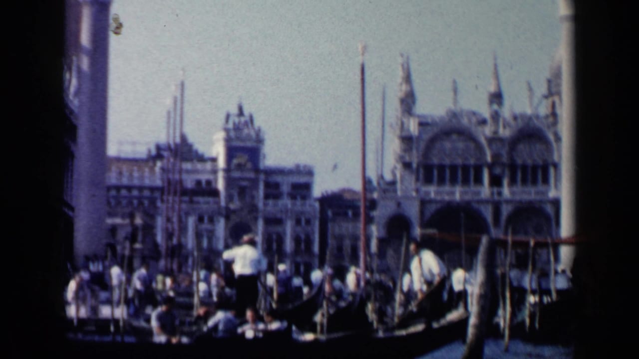 Gondola with gondolier and passengers passing in front of ornate Venetian waterfront buildings.