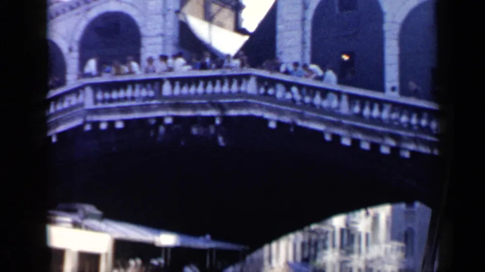 1960 Venice home-movie view of people crossing the Rialto Bridge with canal traffic below.