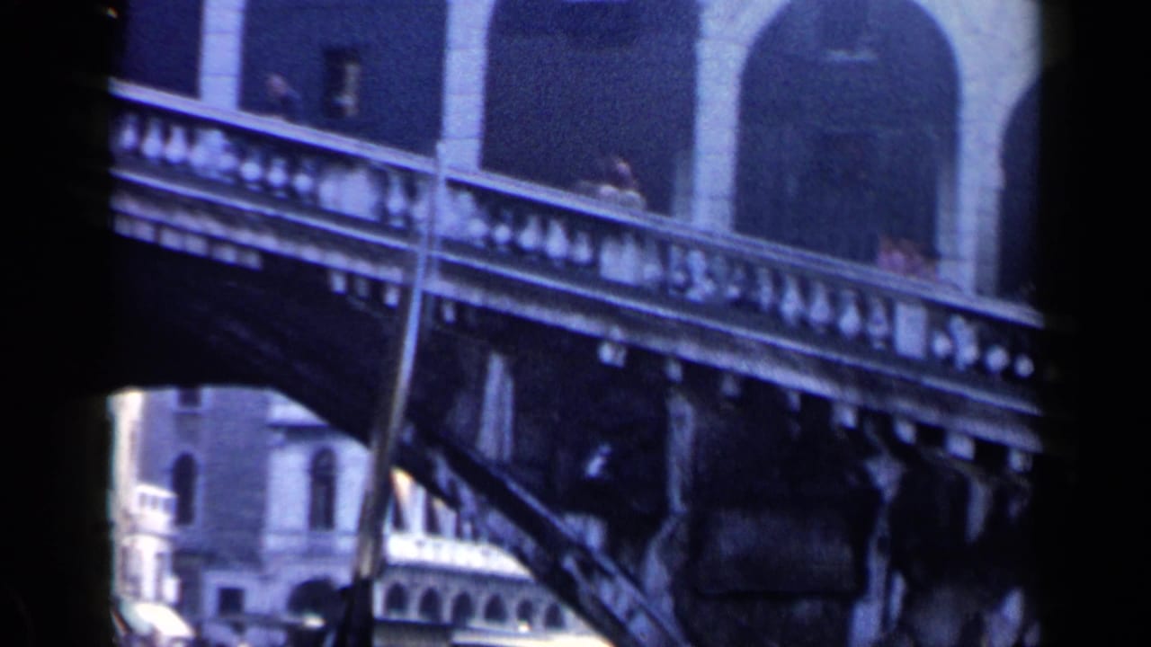 Rialto Bridge arches and balustrade seen from a moving boat on a Venice canal.