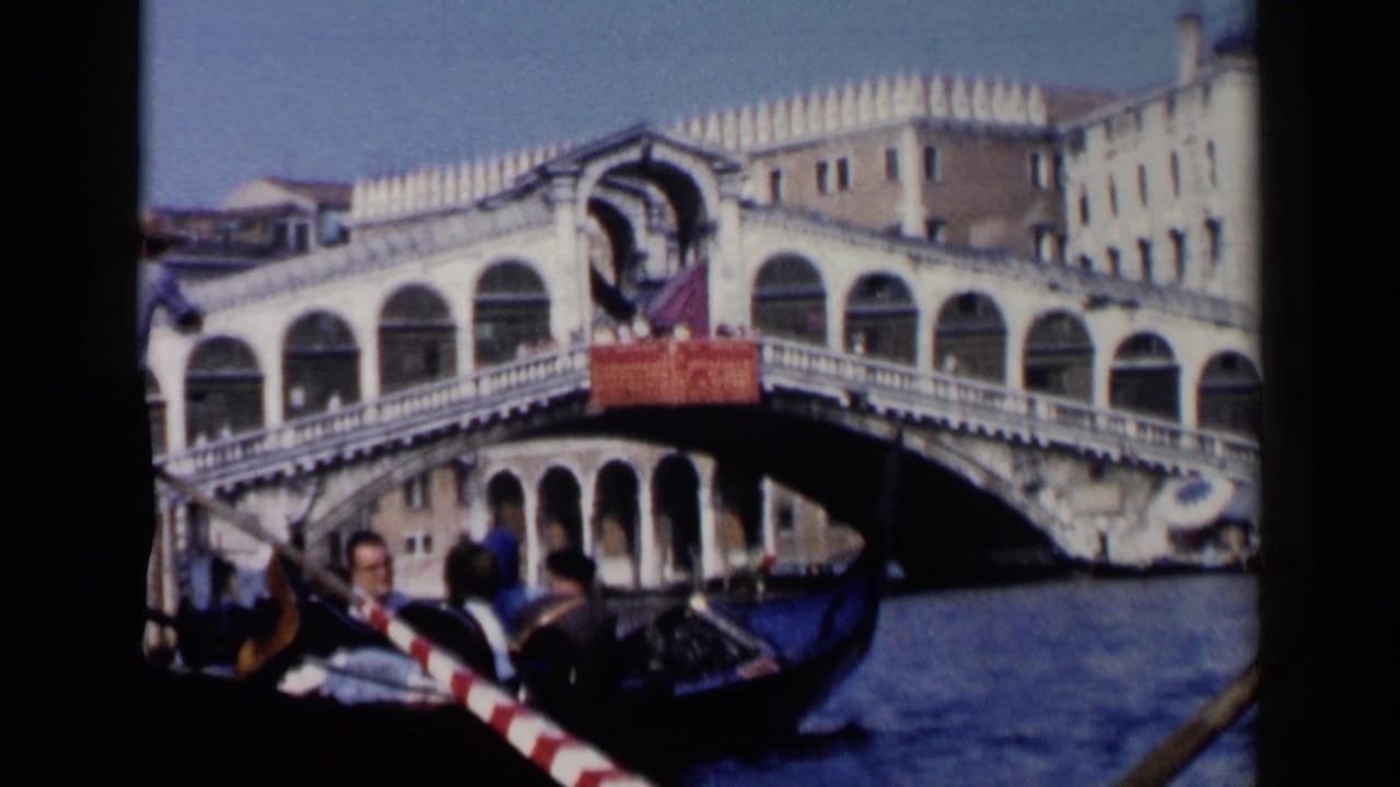 Gondola passenger view toward the Rialto Bridge over Venice canal water.