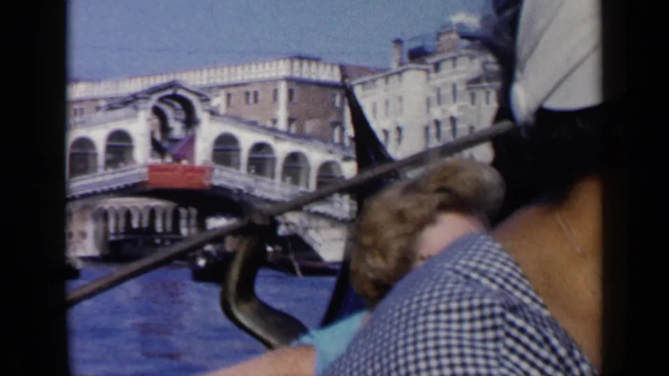 1960 Venice gondola ride with passengers close to camera and the Rialto Bridge visible across the canal.