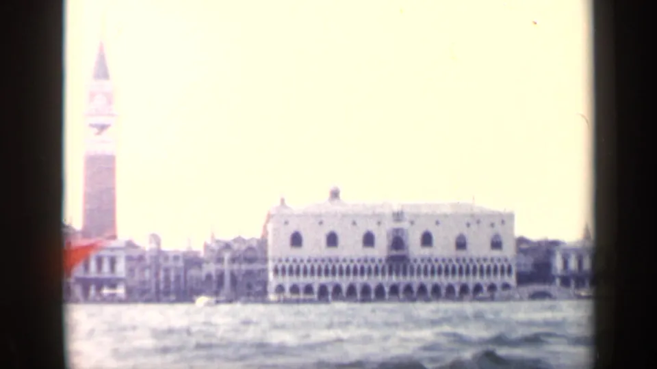 1960 Venice 8mm frame showing the Doge's Palace and St. Mark's Campanile across the water, with bright exposure and soft color.