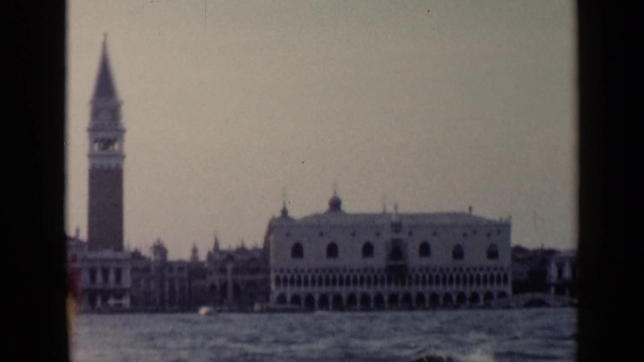 Campanile and Doge's Palace seen across rippled water from a boat.
