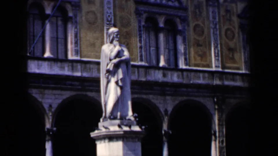 1960 Venice home-movie frame showing a stone statue in front of an ornate arched facade near the waterfront.
