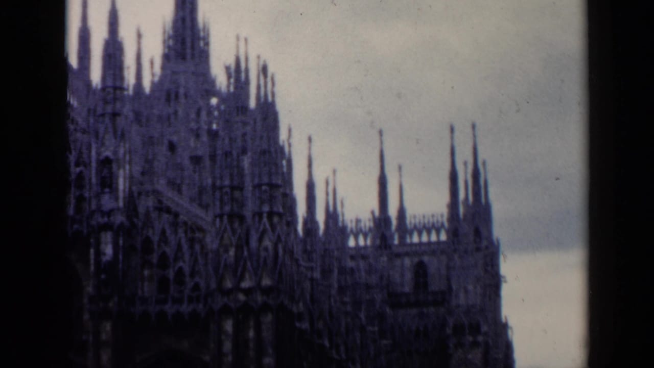 Ornate Gothic church spires rising against a cloudy sky with dark film borders.
