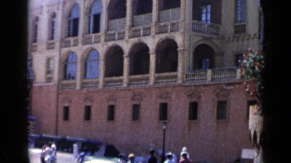 1960 Venice frame of the building's arched balcony row and brick base, with small pedestrians and street fixtures visible below.