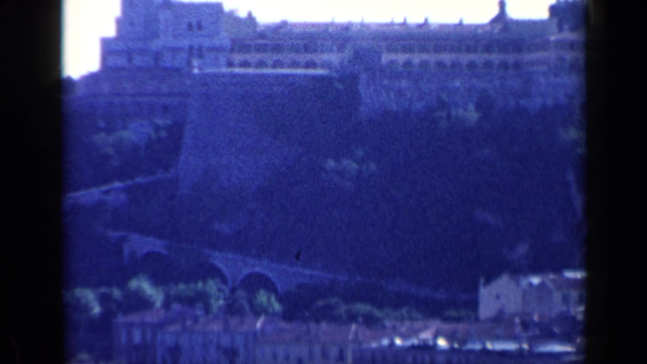 Large stone walls and upper buildings seen across a blue-tinted landscape.