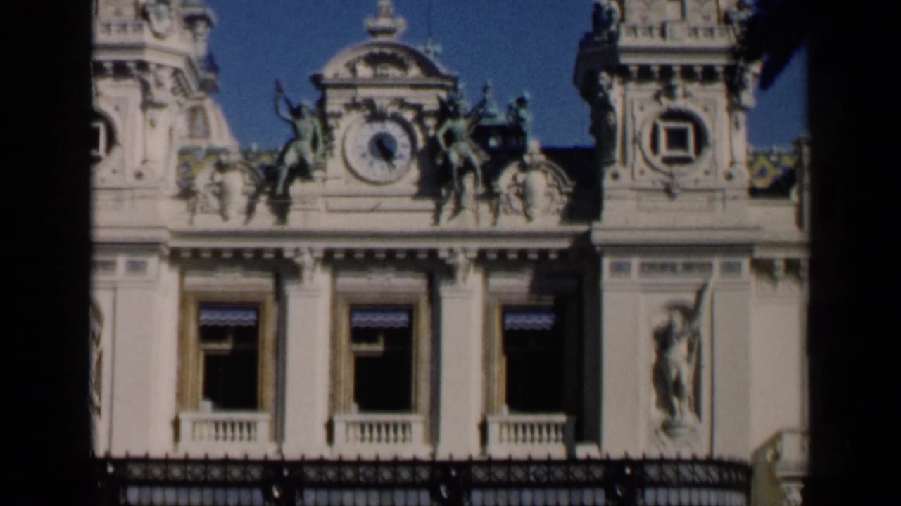 Ornate building facade with clock, sculptures, windows, and dark film border.