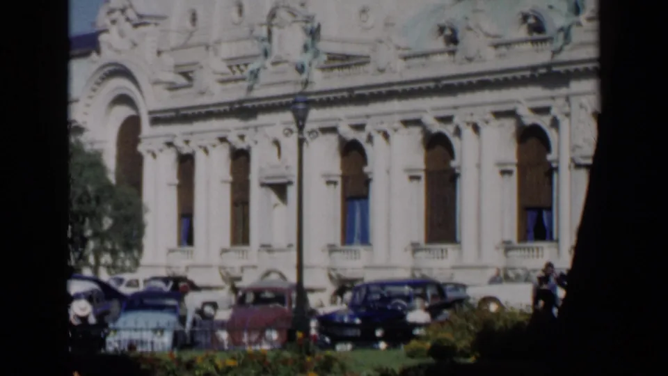 Venice, Italy, 1960 travel footage showing the same ornate building facade with classic cars parked in front and distant pedestrians at the right edge.