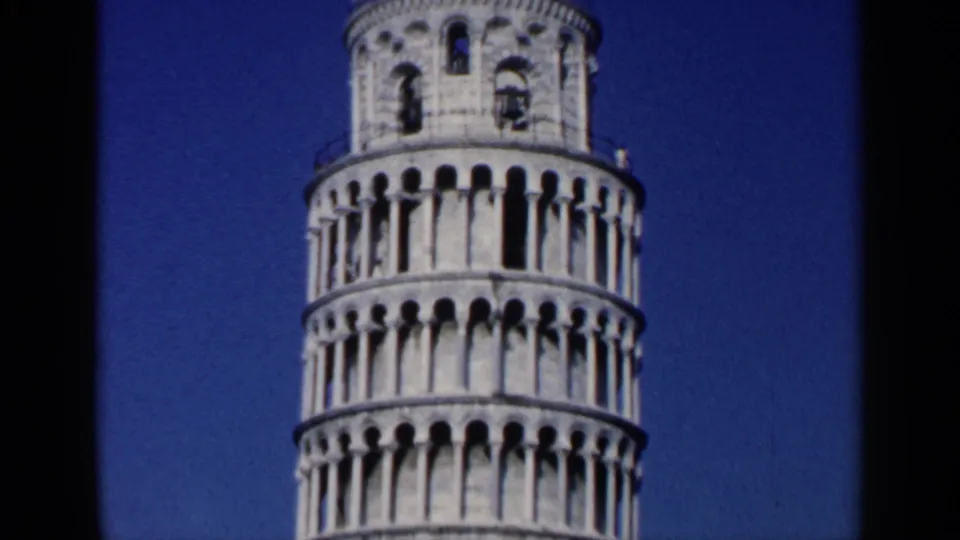 1960 8mm travel frame showing the upper portion of the Leaning Tower of Pisa with arched stone levels against blue sky.