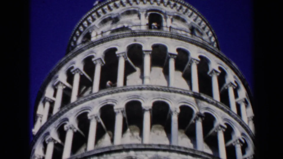 1960 8mm frame of the Leaning Tower of Pisa from below, emphasizing its curved arcade levels and shadowed openings.