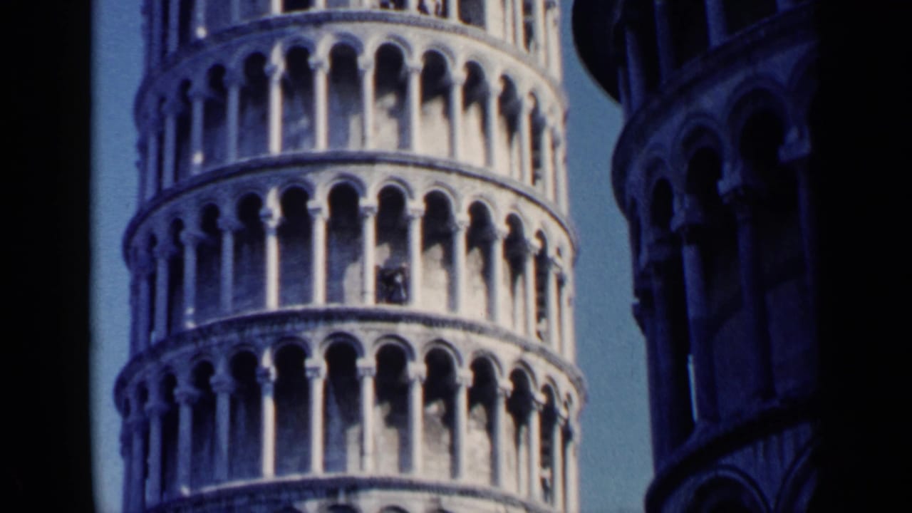 Close upward view of the Leaning Tower of Pisa with arched galleries and blue sky.