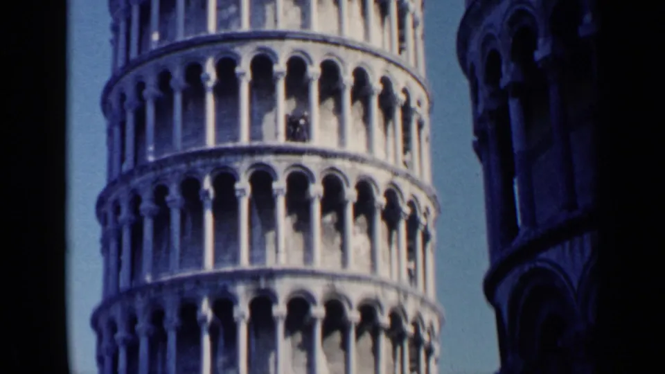 1960 8mm frame of the Leaning Tower of Pisa, with small tourist figures visible among the upper arched openings.